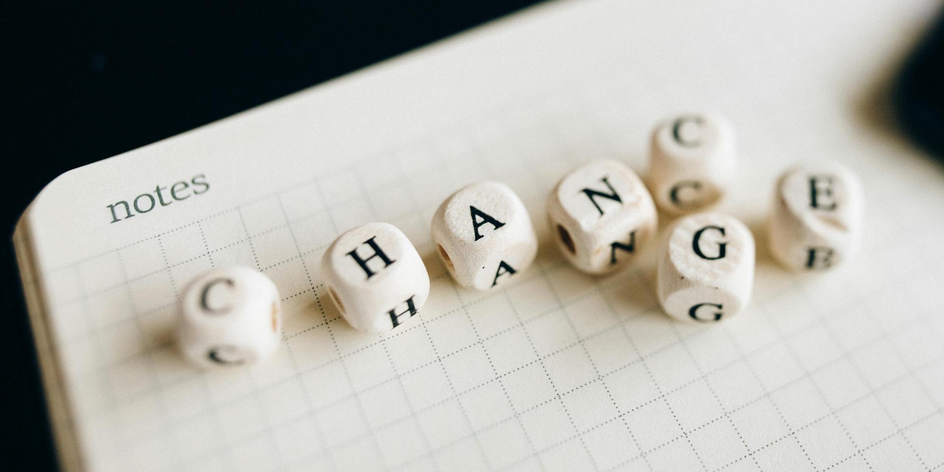 Multiple letter dice showing the words "Change" and "Chance" on an open notebook