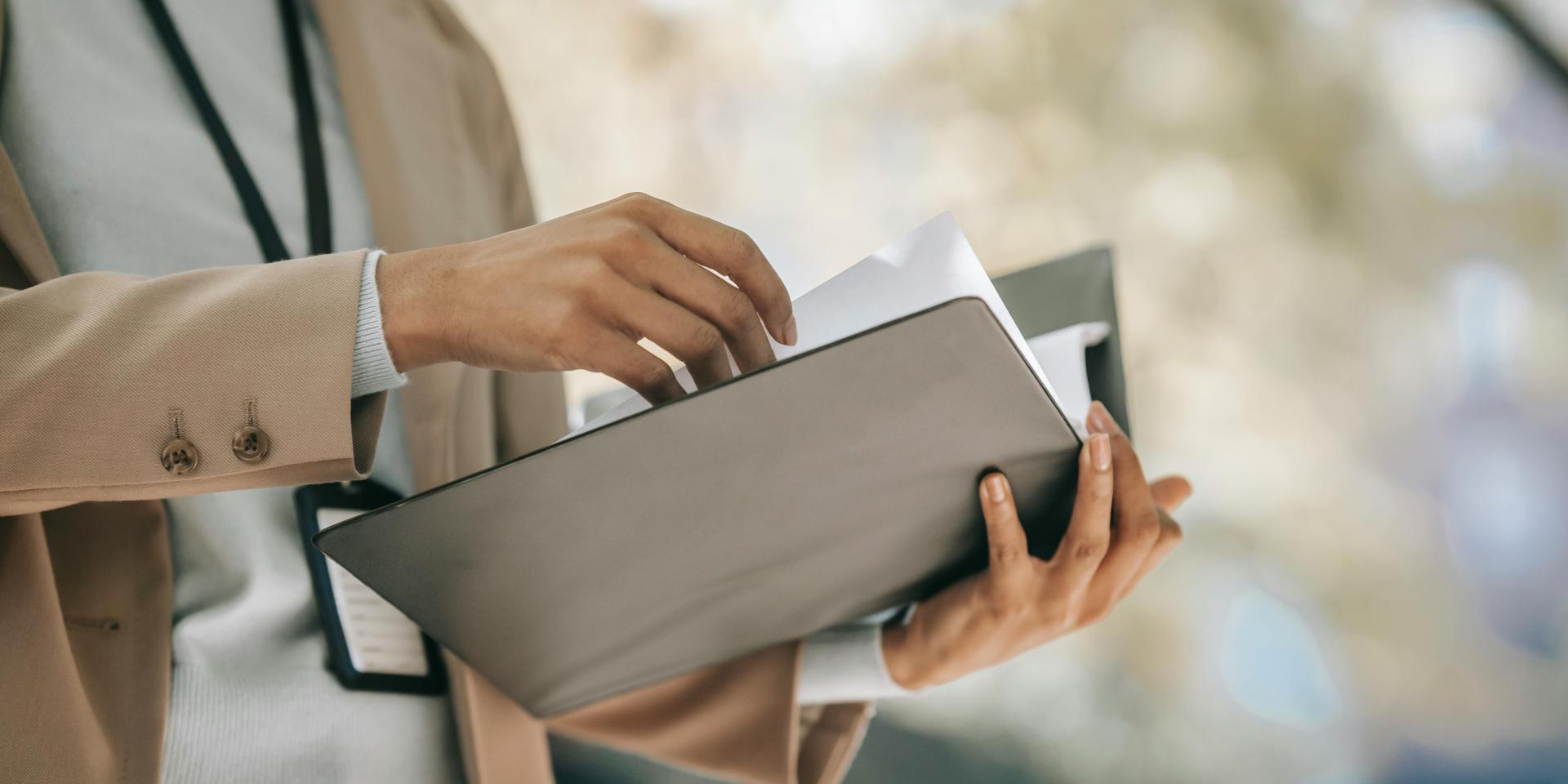 A person holds a binder, turning pages