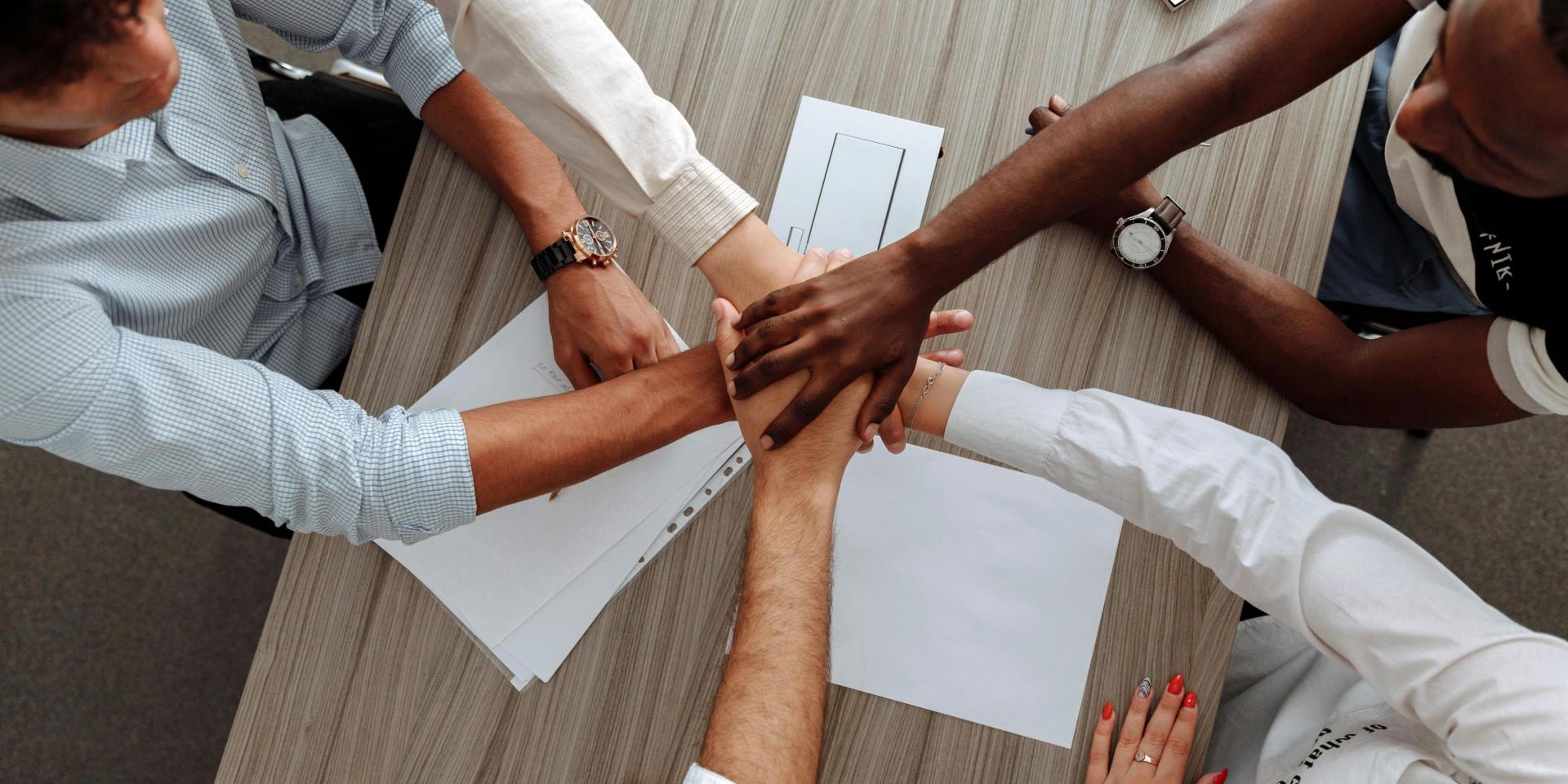 People putting their hands together in the middle of a table
