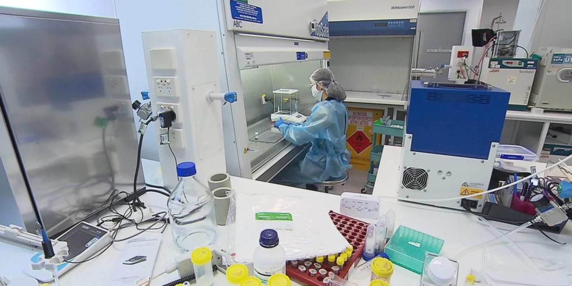 A scientist works under a hood in a laboratory