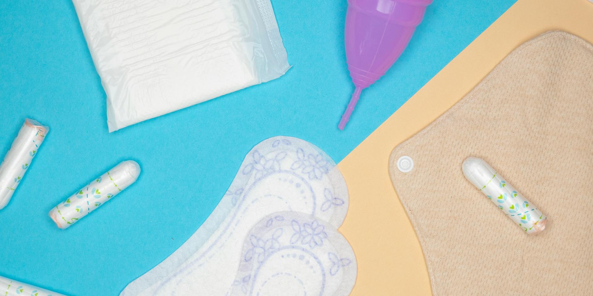 Flat lay of menstrual prodcuts, including cup, pads, and tampons