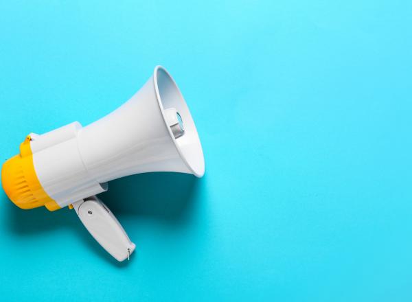 A white and yellow megaphone laying on its side against a teal background