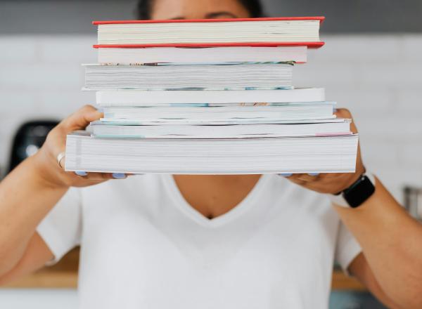 A person holding a stack of books in their hands