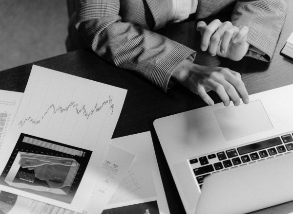 A person sitting at a table looking at a laptop and documents