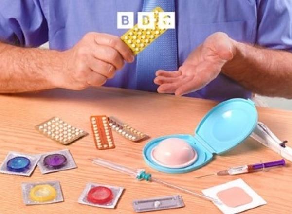 Man sitting in front a table with a variety of different contraceptive methods