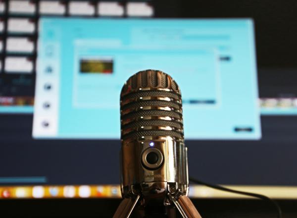 Podcast microphone with a computer in the background
