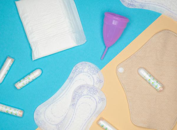 Flat lay of menstrual prodcuts, including cup, pads, and tampons